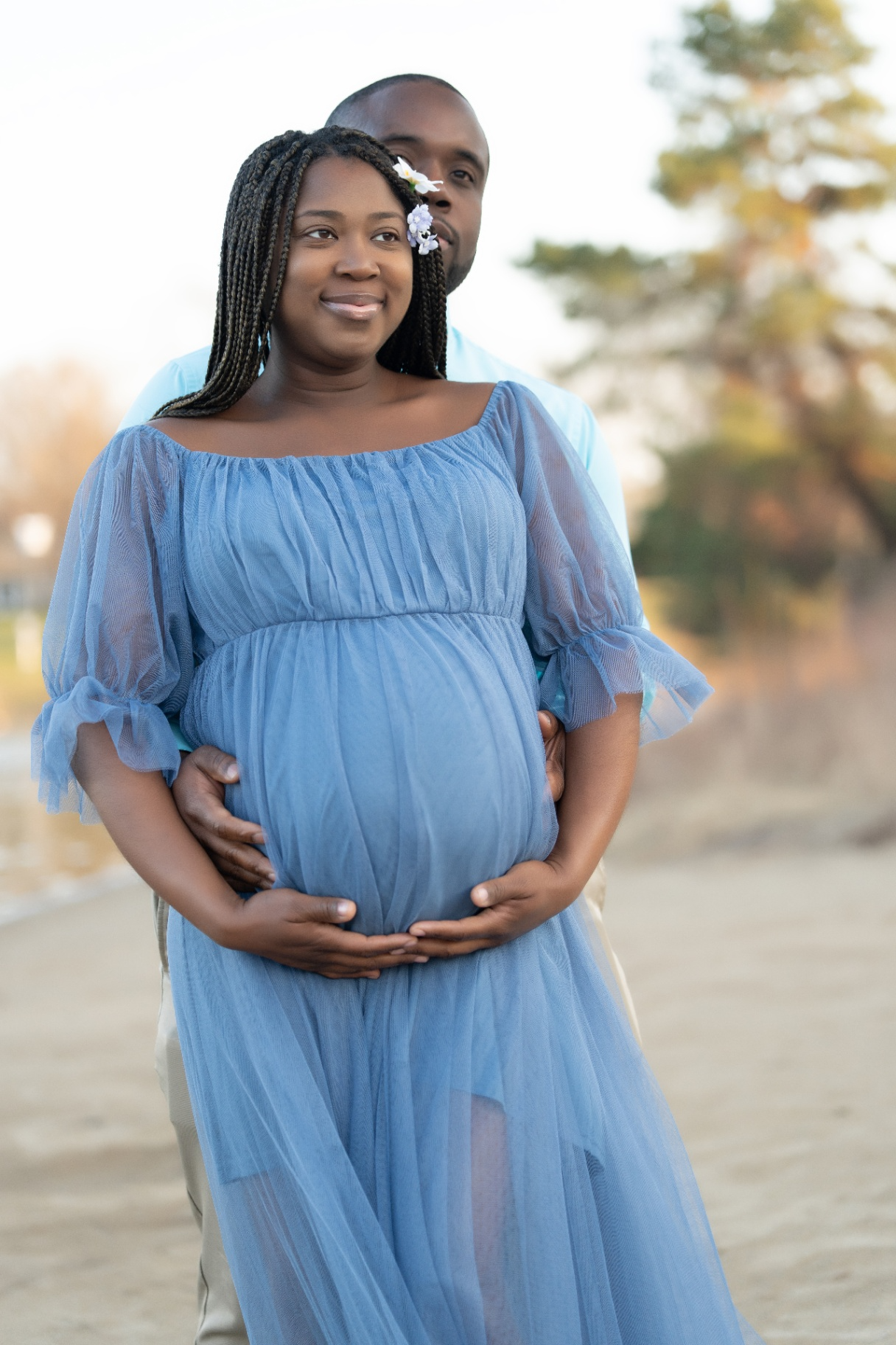 Maternity portrait of expecting couple in blue tulle gown at golden hour