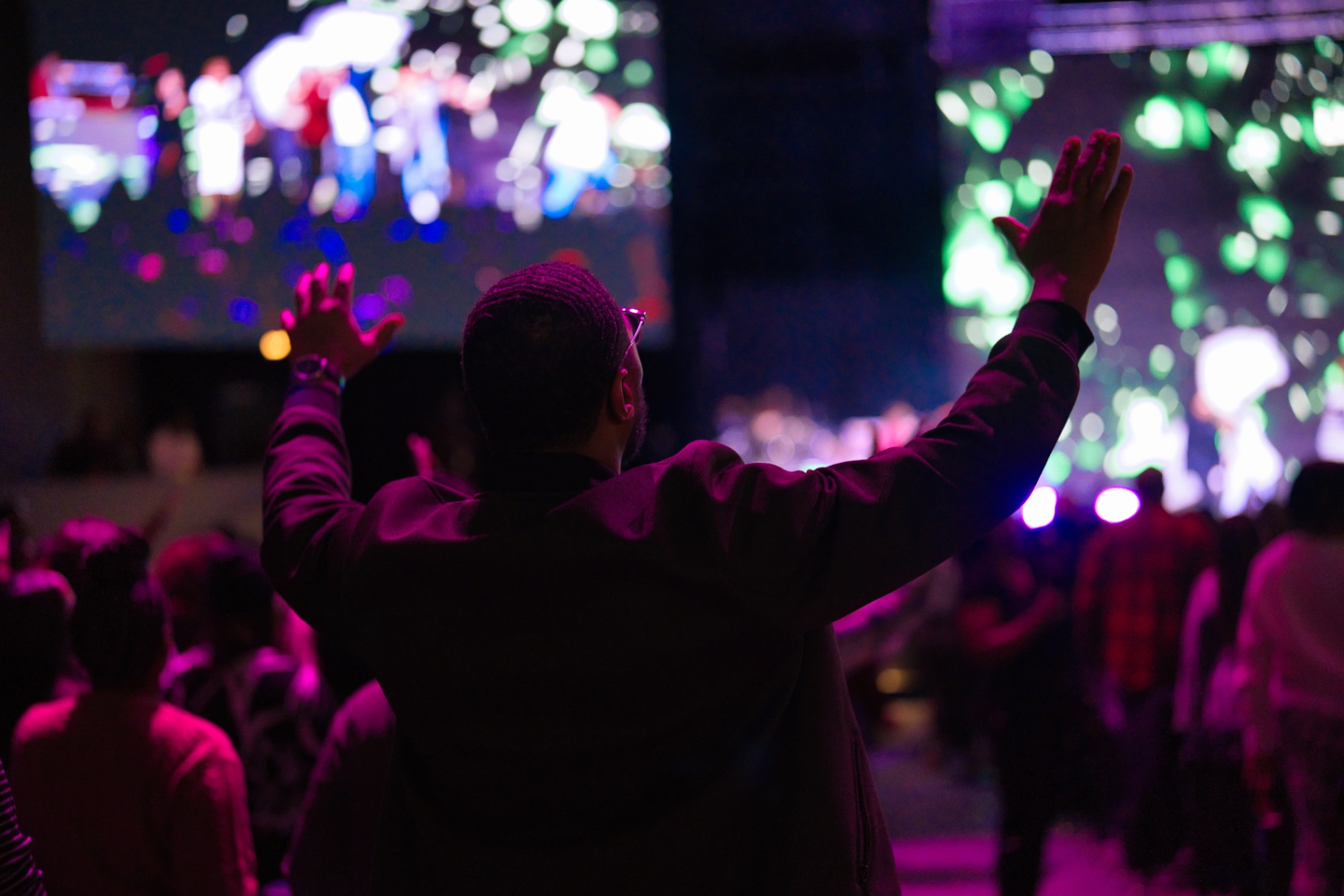Worshipper with raised hands amid stage lights